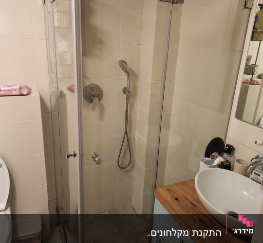 מקלחת עם דלת זכוכית וראש מקלחת ידני
